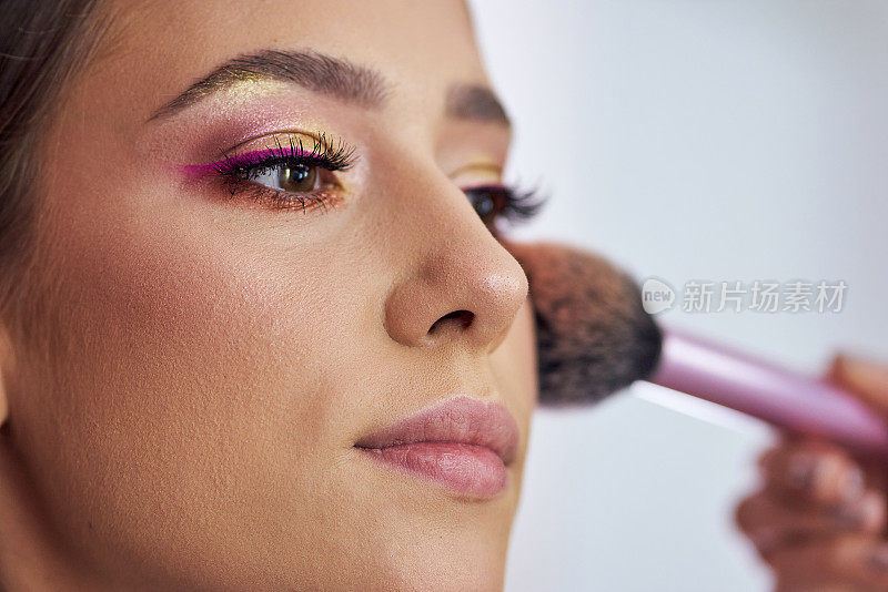 专业的化妆师用一种深色的古铜色化妆品为顾客塑造鼻子轮廓