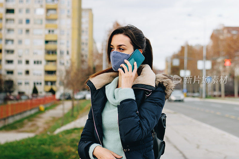 女人用保护口罩使用手机户外库存照片