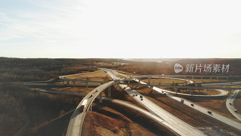 红色拖拉机半长途卡车和汽车驶出匝道空中立交桥，立交桥交通视图在美国中西部公路运输照片系列