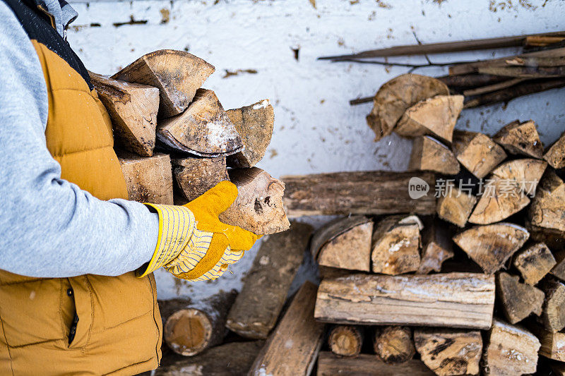 近距离观察一个从柴棚里扛木柴的男人。