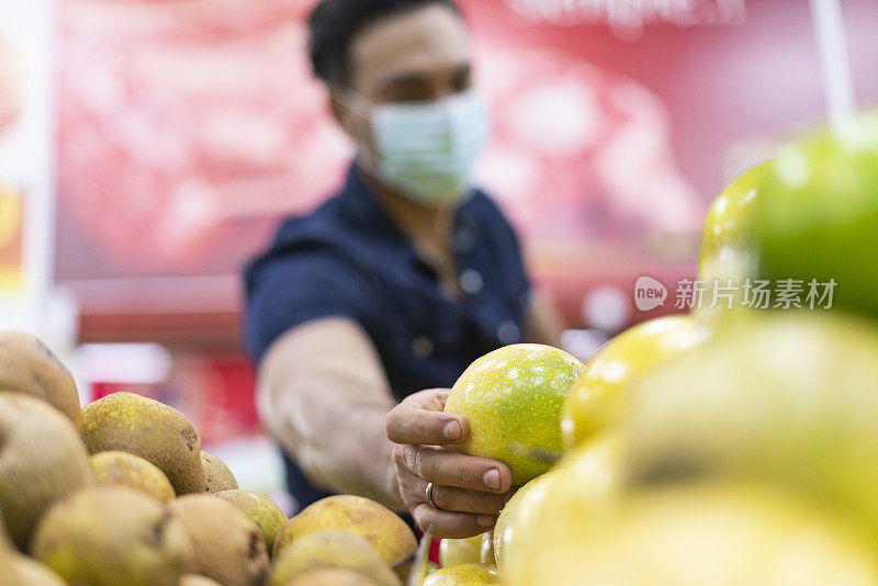 拉丁裔男性在杂货店购物时戴着面具