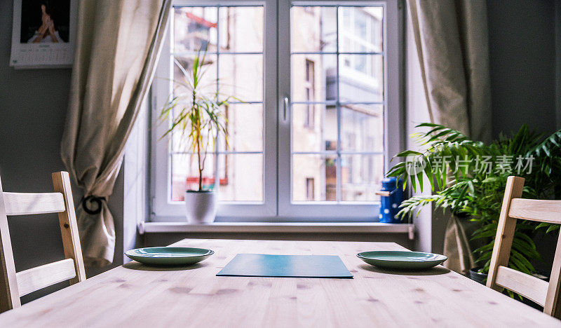 现代室内设计的厨房空间用小桌子，用简单的椅子和植物装饰。