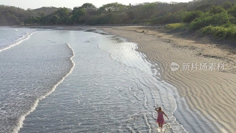 鸟瞰图的女人走下沙滩在日出