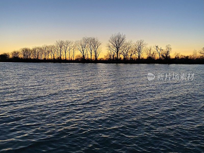 夕阳越过水面和远处的林木线