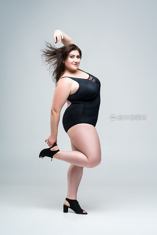 性感大码时装模特在黑色连体泳衣，胖女人在灰色的背景内衣