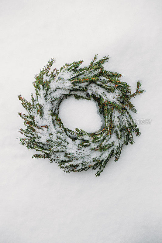 由天然冷杉树枝制成的白雪覆盖的圣诞花环