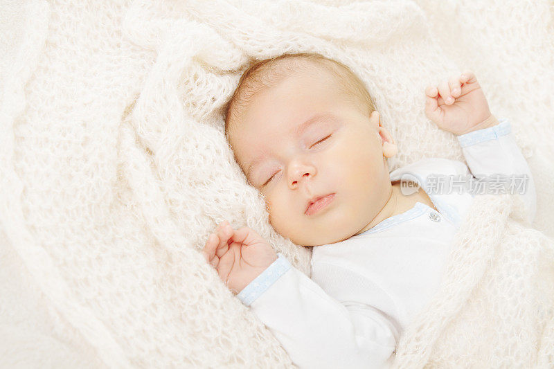 刚出生的婴儿正在睡觉，盖着毛毯