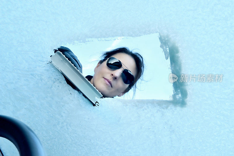 冬天开车-女人从挡风玻璃上刮冰