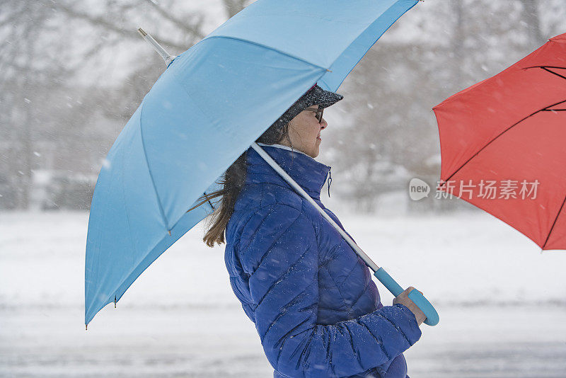 十几岁的女孩撑着伞在下雪的街道上