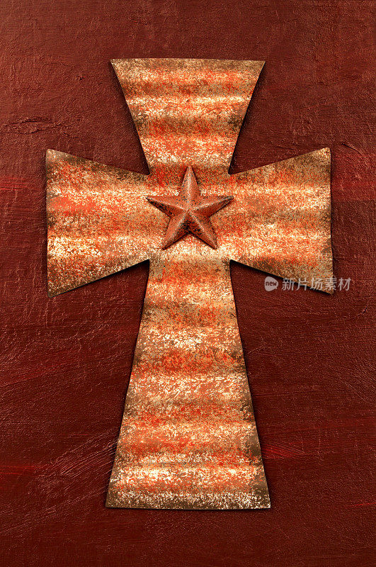 锈迹斑斑的波纹金属十字架在漆成桔红色的背景上