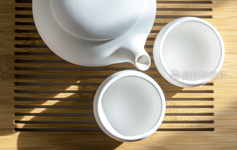 陶器茶壶和杯子在阳光下的桌子上
