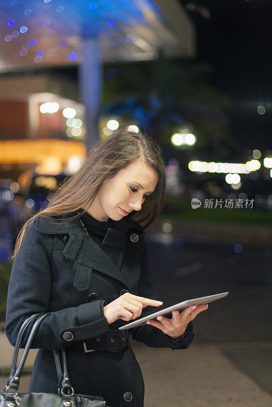 年轻女子在城市街道上使用平板电脑