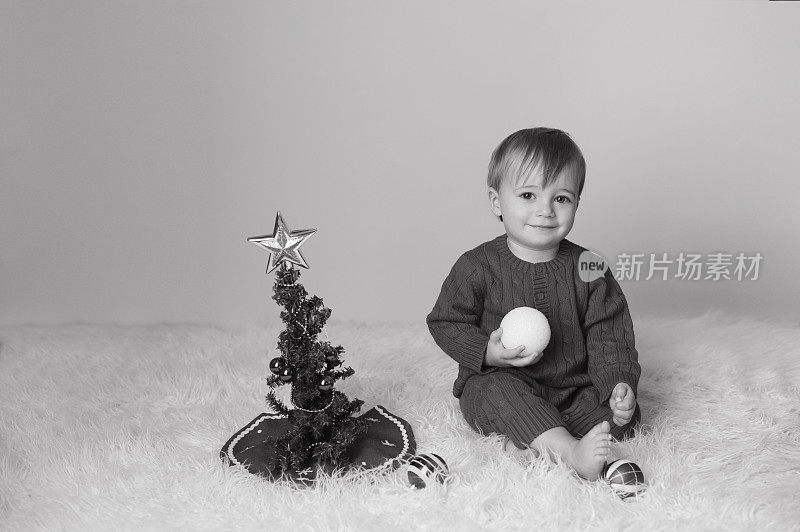 微笑的婴儿坐在毛旁边的迷你圣诞树