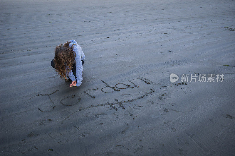 女孩把她的手放在潮湿的沙子里