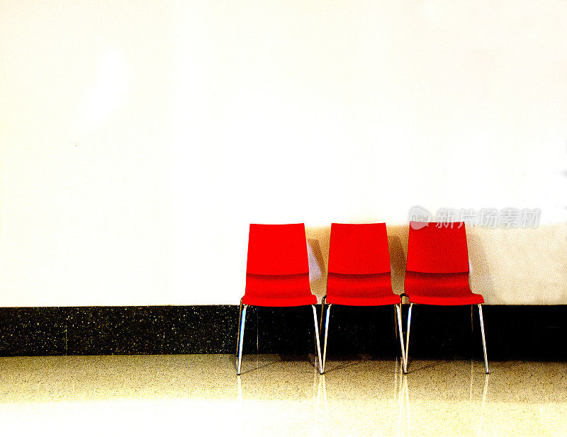 三把红椅子靠着白墙