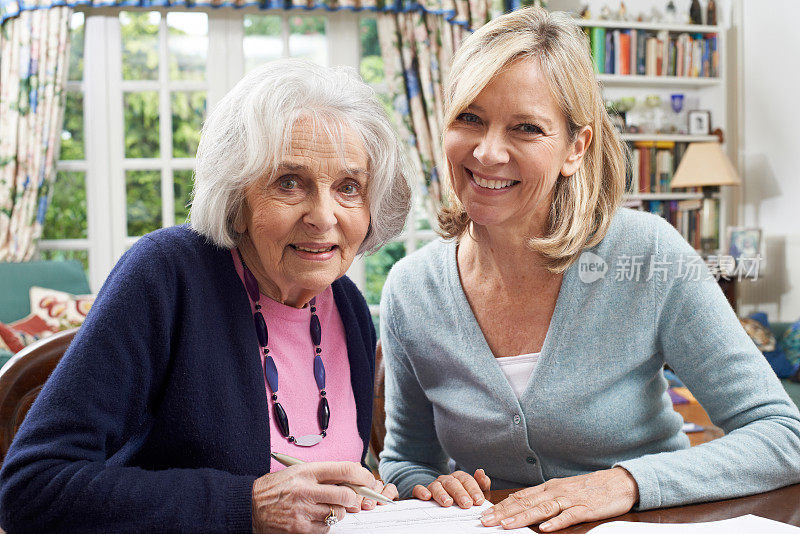 女邻居帮助老年妇女填写表格