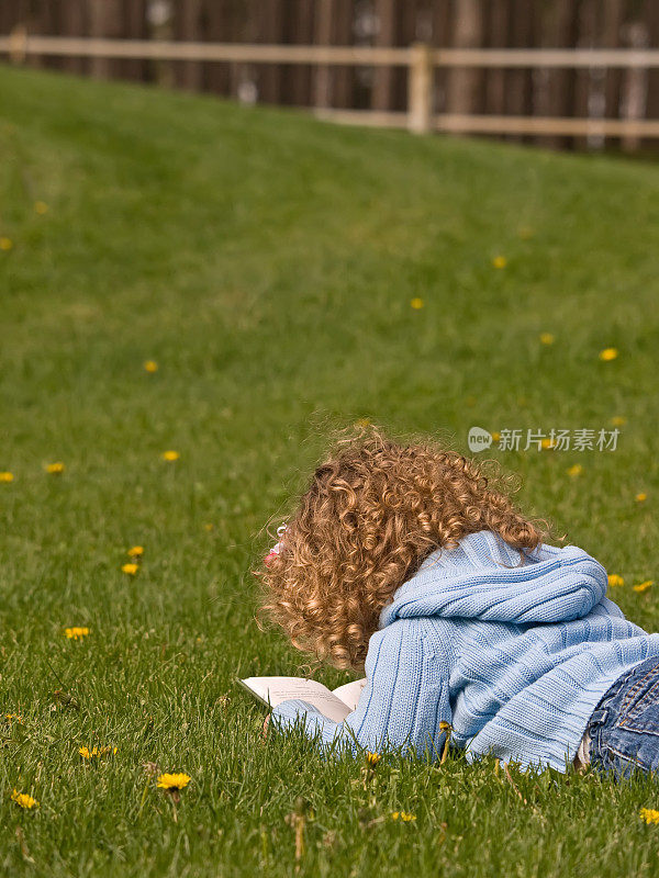 小女孩在草坪上看书