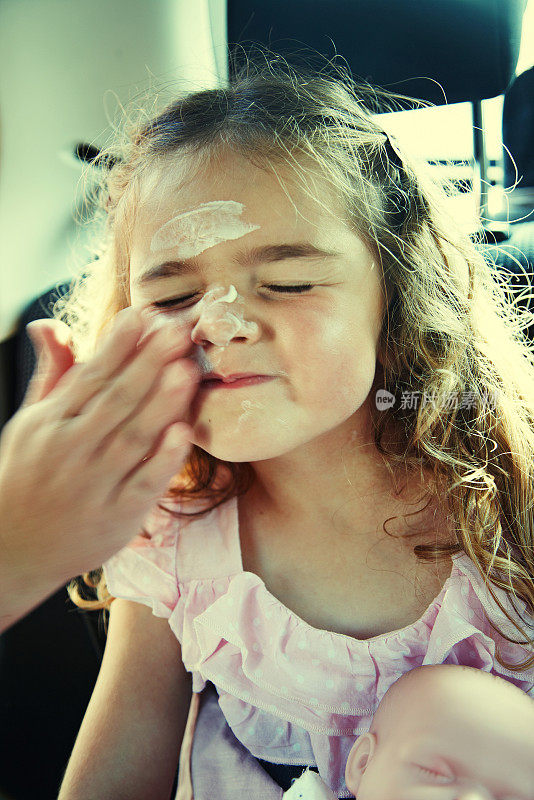 五岁女孩在脸上涂防晒霜