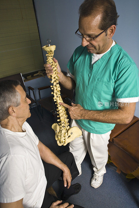 脊椎按摩师抱着老年患者的旋转模型