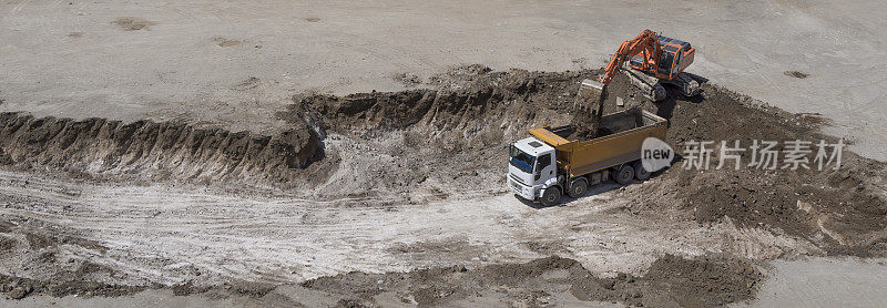 挖掘机挖掘和装载土到一辆自卸卡车