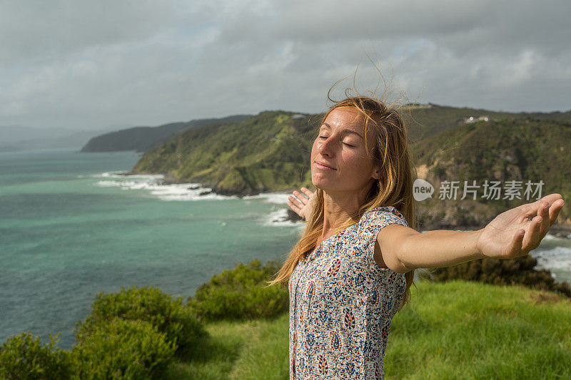 年轻快乐的女人双臂伸向海岸线