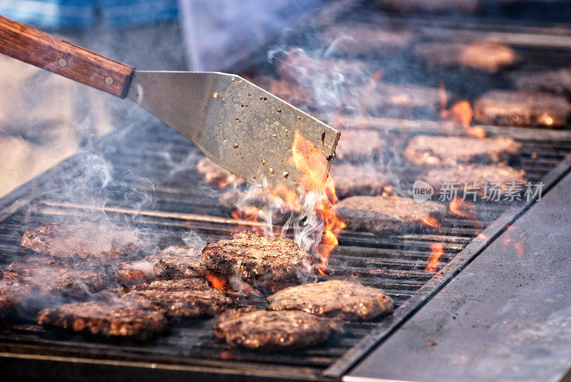 社区烧烤烹饪汉堡，烟雾和火焰。