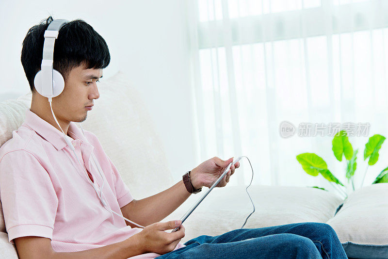 年轻的亚洲人戴着耳机欣赏音乐