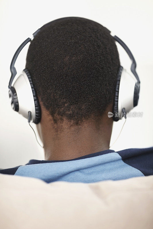 一个男孩在耳机上听音乐的特写后视图