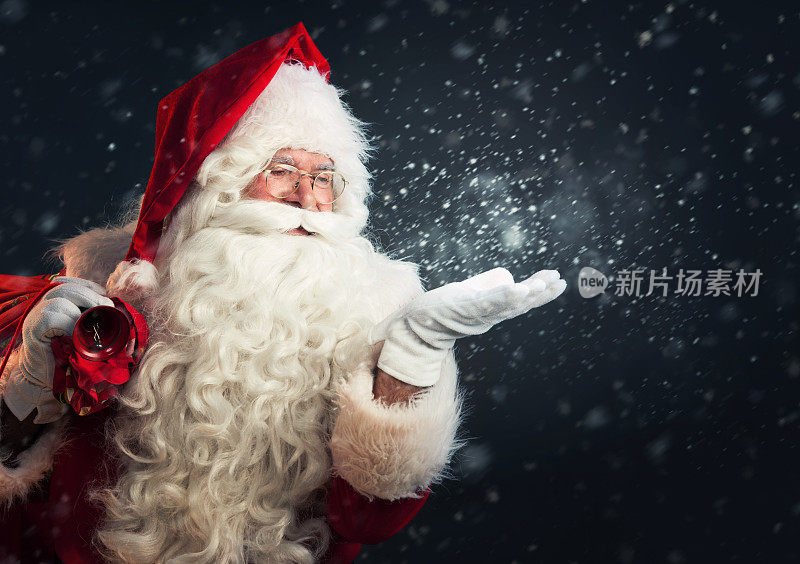 圣诞老人用手吹着魔法雪