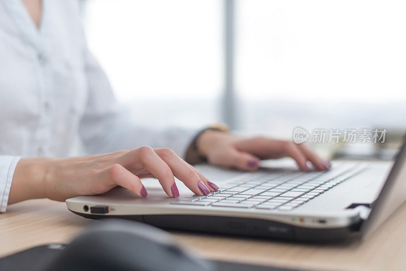 和笔记本女一起写博客。女性的手在键盘上。