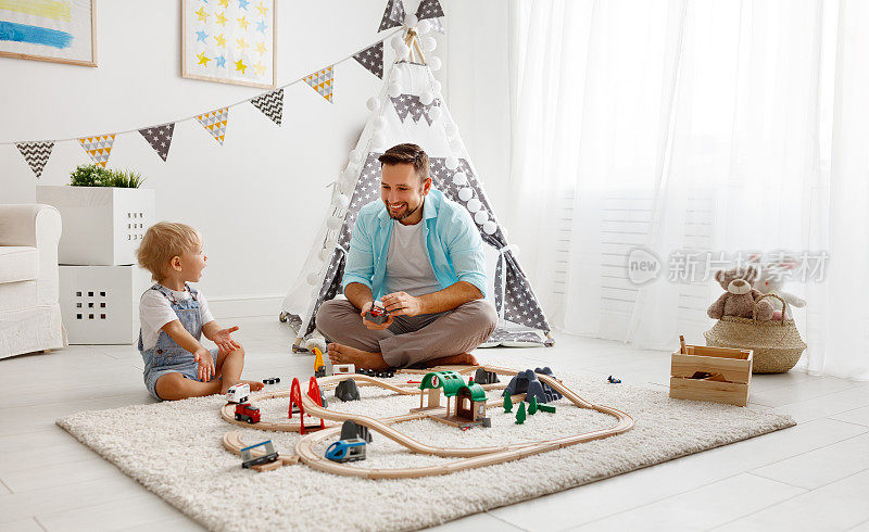 快乐的家庭，爸爸和孩子在玩具铁路玩在游戏室