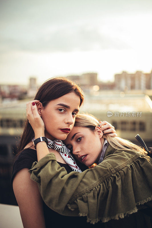 美丽的年轻双胞胎姐妹放松在一个城市的屋顶上
