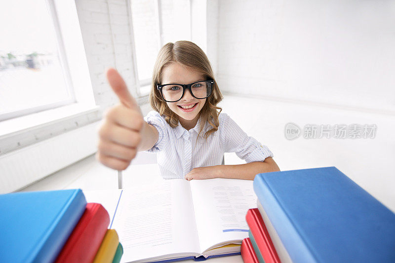 快乐的女学生对着书竖起大拇指