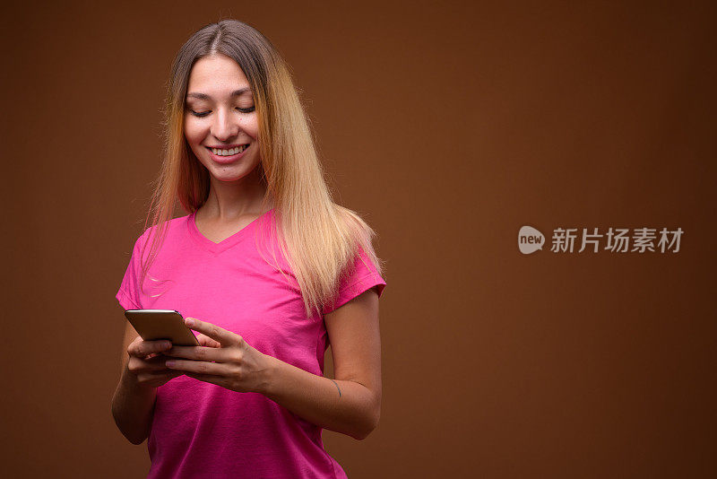 工作室拍摄的年轻美丽的女人穿着粉红色的衬衫，以彩色的背景