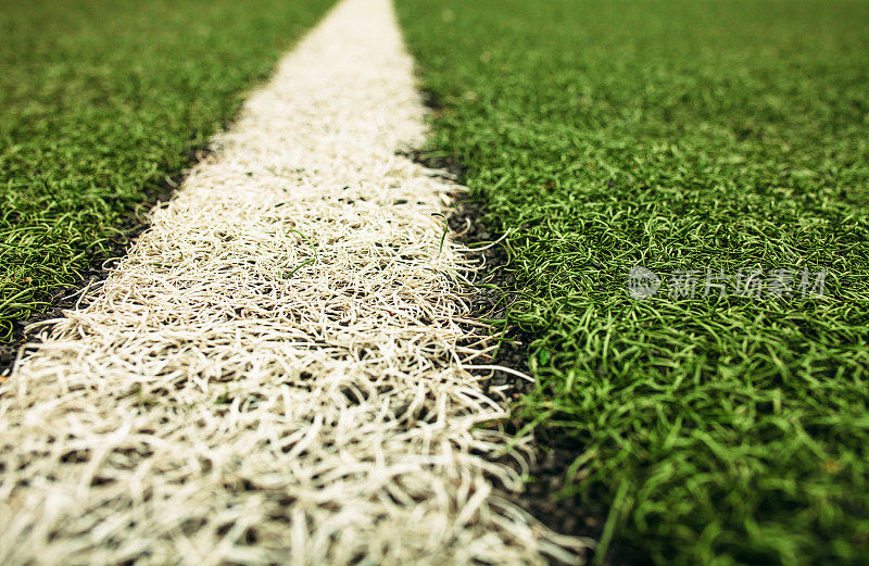 绿色的人造草地足球场。绿色足球场背景上的白线。