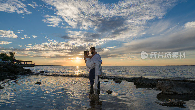 日落时分，一对年轻夫妇在海滩上。