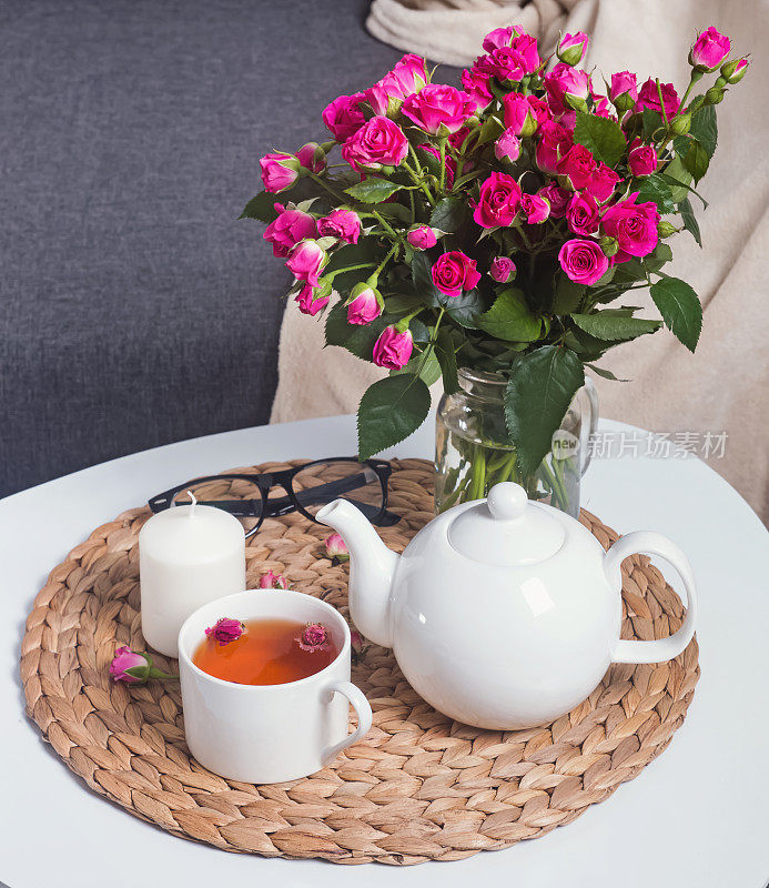 花草茶，粉红玫瑰，白色咖啡桌上的蜡烛。