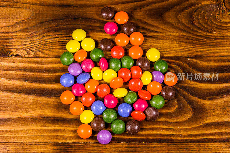一堆五彩糖果放在一张木桌上。俯视图
