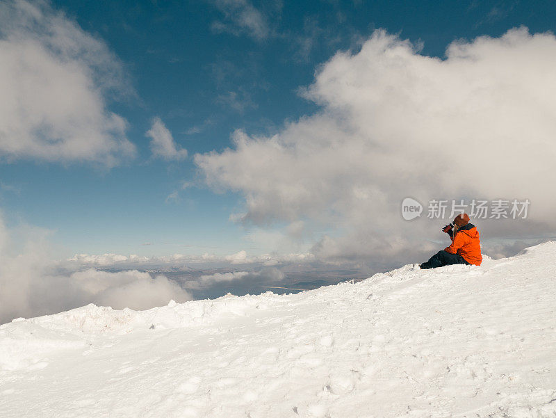 女性高山攀登者在冬季日出时在高海拔的山峰上喝咖啡