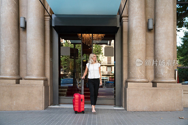 美丽的旅行女子走出酒店