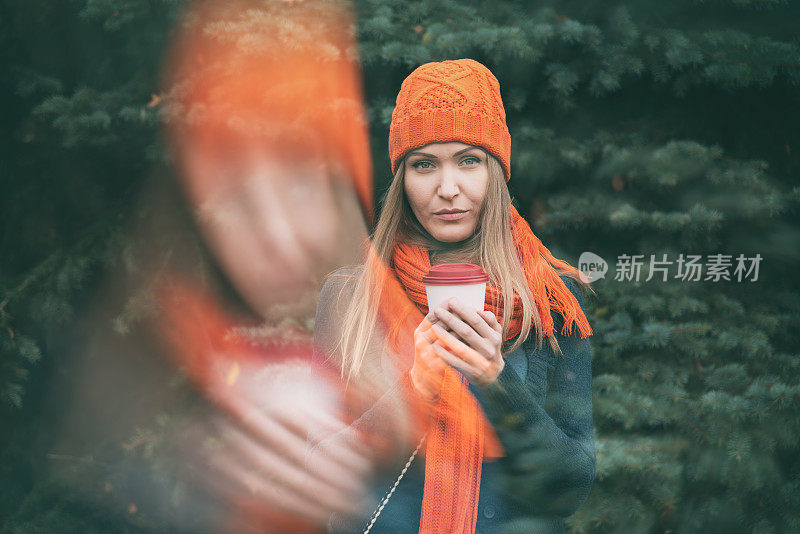 年轻女子在秋天的户外喝茶