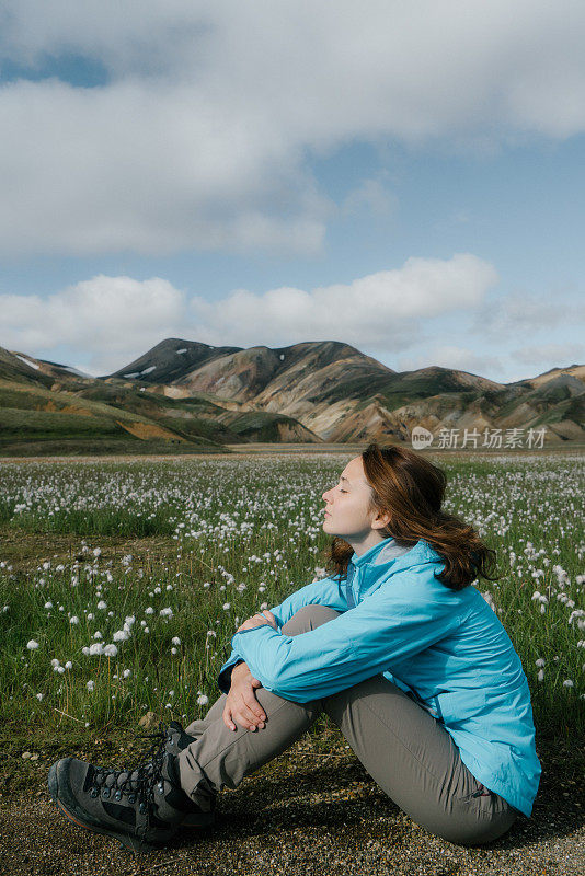 在冰岛的Landmannalaugar，一名妇女在五颜六色的山附近休息