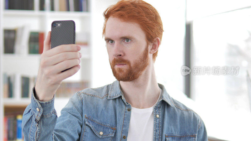 年轻随意的红发男子用智能手机自拍
