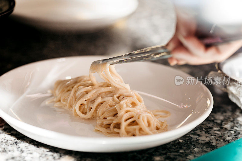 厨师把意大利面条整齐地放在白色盘子里