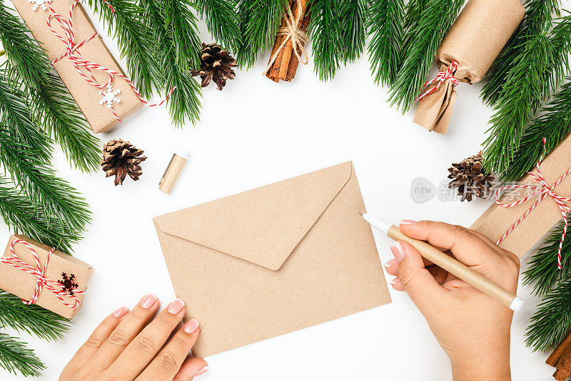 在给圣诞老人写新年信的概念中，妇女递过空白的工艺信封，信封上有圣诞树树枝、锥形礼盒和礼盒的框架
