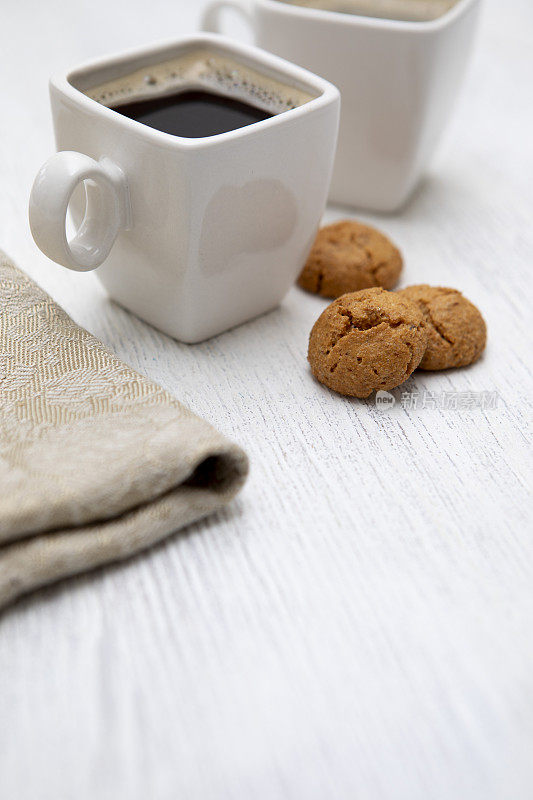 白色木桌上放着两个意式咖啡杯，还有杏仁饼干和餐巾纸，还有复印空间