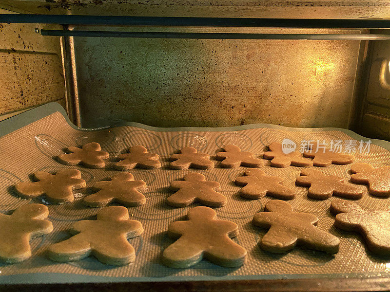 近距离图像的一排排生的，自制的姜饼人饼干硅烤片，切，姜饼面团形状与饼干切割烹饪在对流烤箱，家庭烘烤，重点前景