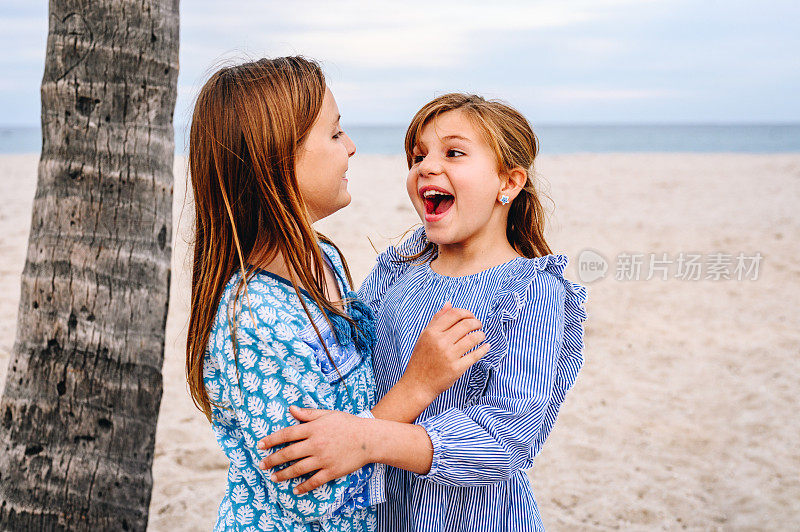 可爱的姐妹们在田园诗般的海滩上笑着，孩子们在度假