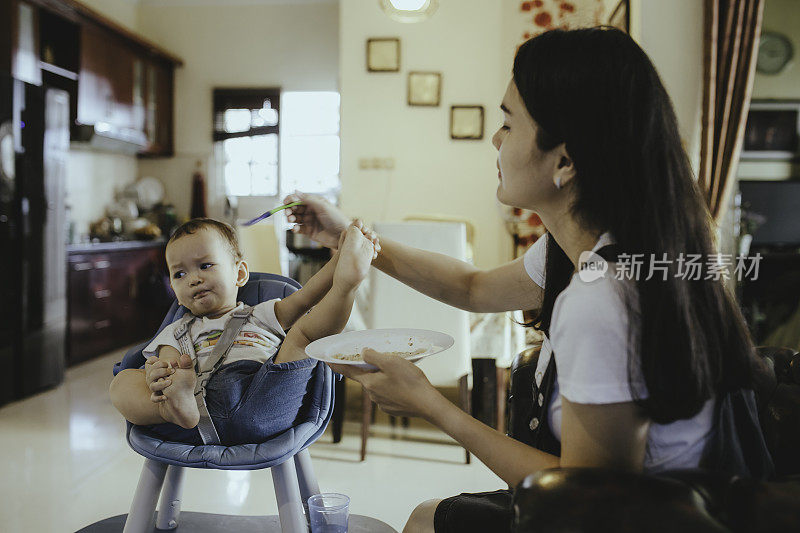 亚洲年轻母亲喂她的婴儿食品