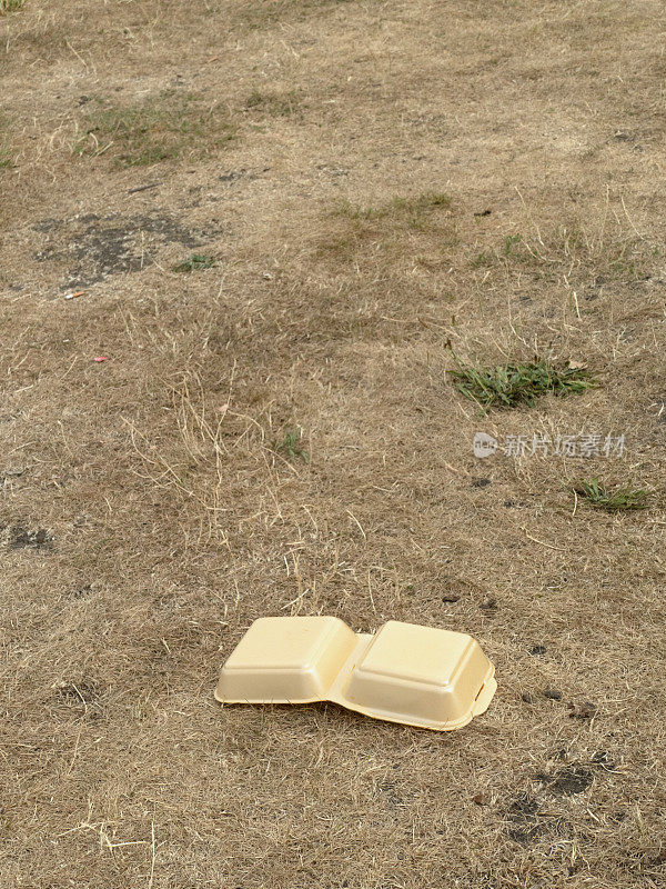 烧焦的草坪上丢弃的食品纸盒